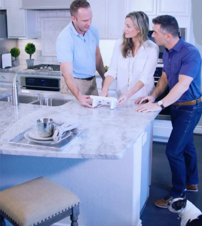 Three people standing around a kitchen island with a dog.